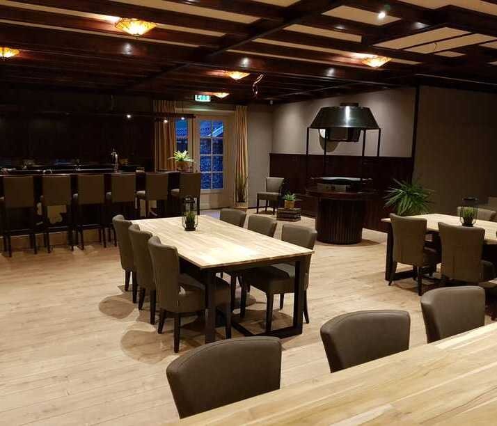 Ruime eetruimte met tafels, stoelen en bar bij De Zwerfkei